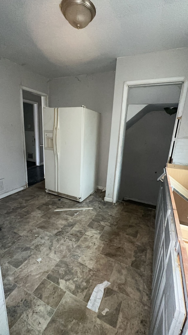 kitchen with white refrigerator with ice dispenser and a textured ceiling