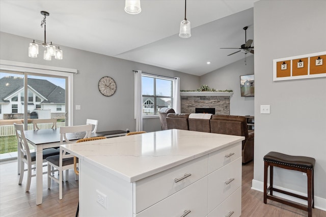 kitchen with white cabinets, decorative light fixtures, vaulted ceiling, and a kitchen island