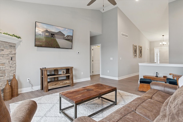 living room with hardwood / wood-style floors, ceiling fan with notable chandelier, and high vaulted ceiling