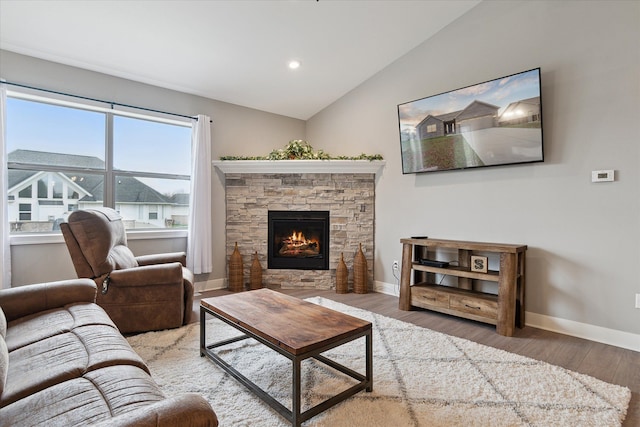 living room featuring a stone fireplace, wood-type flooring, and vaulted ceiling