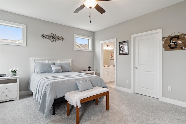 carpeted bedroom with ceiling fan, ensuite bathroom, and multiple windows