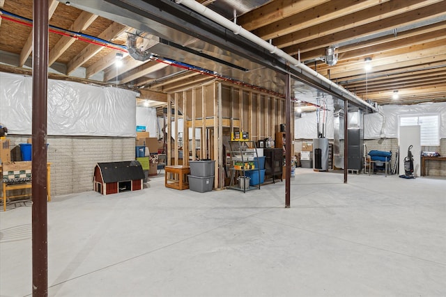 basement featuring brick wall, heating unit, and water heater