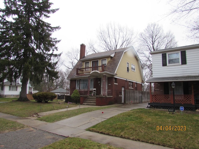 view of front of property with a porch, a balcony, and a front yard