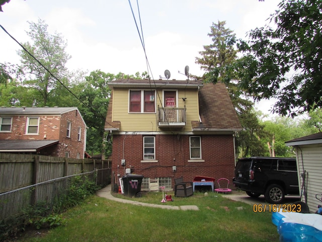 back of property with a balcony and a yard