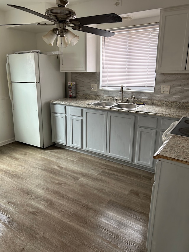 kitchen featuring light wood-style floors, tasteful backsplash, a sink, and freestanding refrigerator