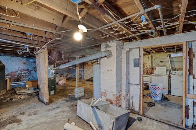 basement with washing machine and dryer and brick wall