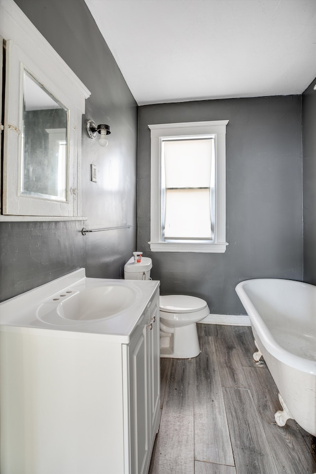 bathroom featuring hardwood / wood-style flooring, vanity, toilet, and a bathing tub