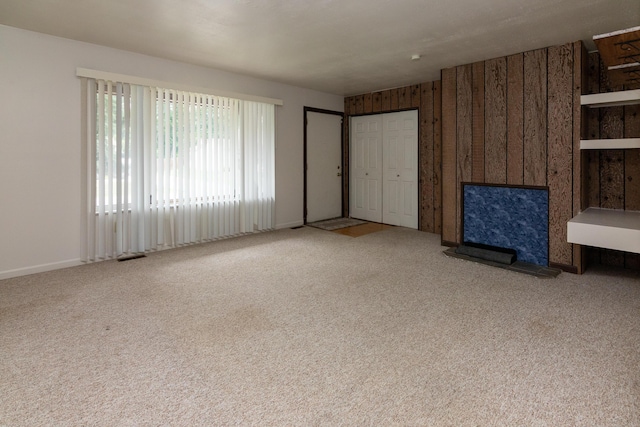 unfurnished living room with light carpet and wood walls