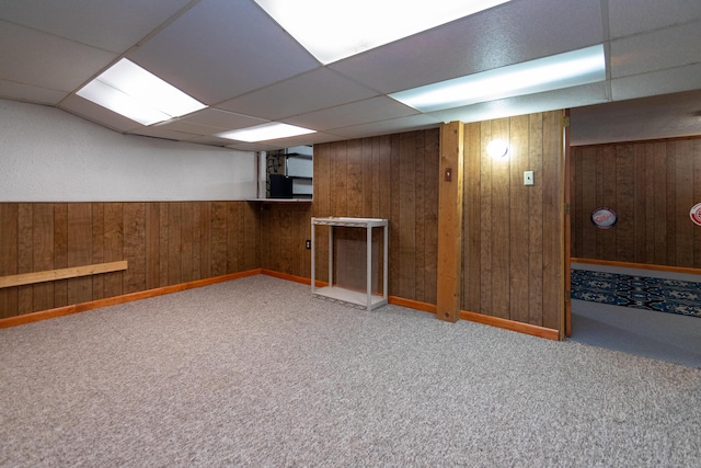 basement with a paneled ceiling, wood walls, and carpet floors