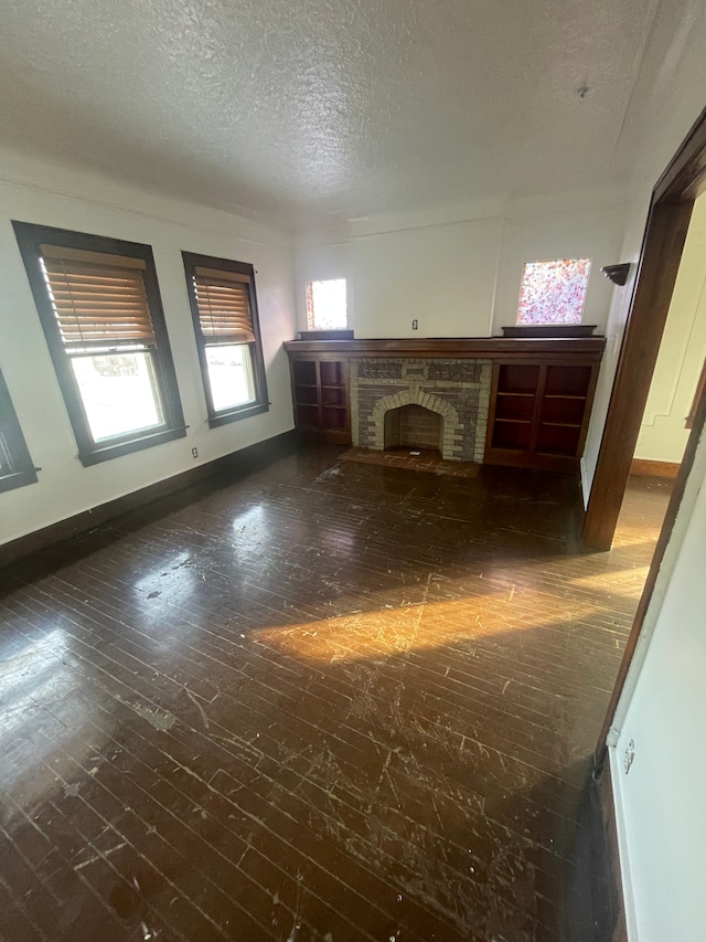 unfurnished living room with a fireplace, dark wood-type flooring, and a textured ceiling