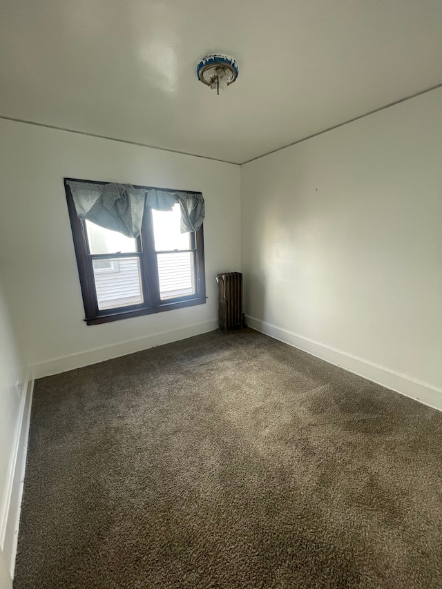 empty room featuring dark carpet and radiator