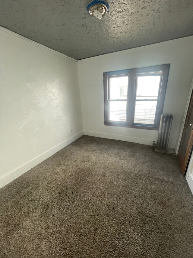 unfurnished room featuring dark carpet, a textured ceiling, and radiator