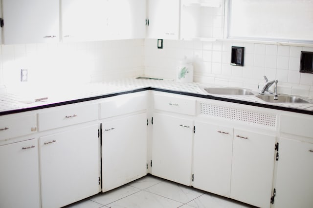 kitchen featuring white cabinets, decorative backsplash, and sink