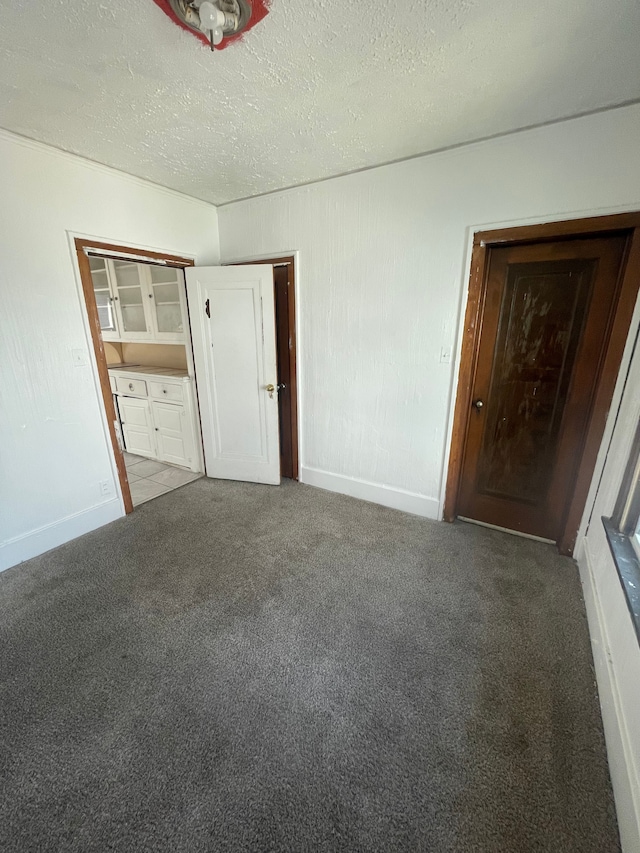 unfurnished bedroom featuring carpet flooring, a textured ceiling, and a closet