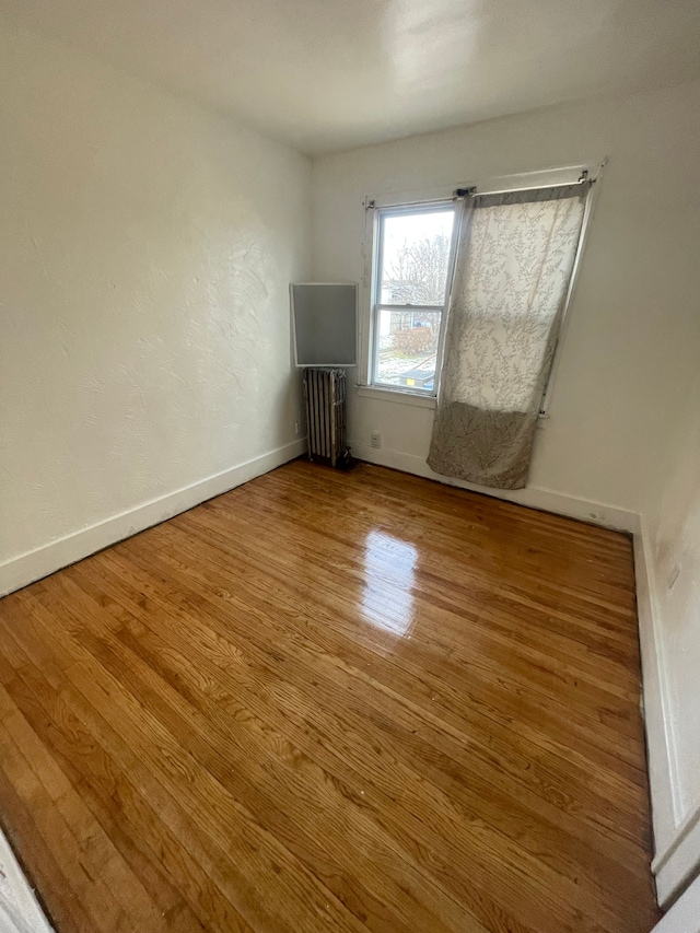 spare room with radiator heating unit and hardwood / wood-style flooring