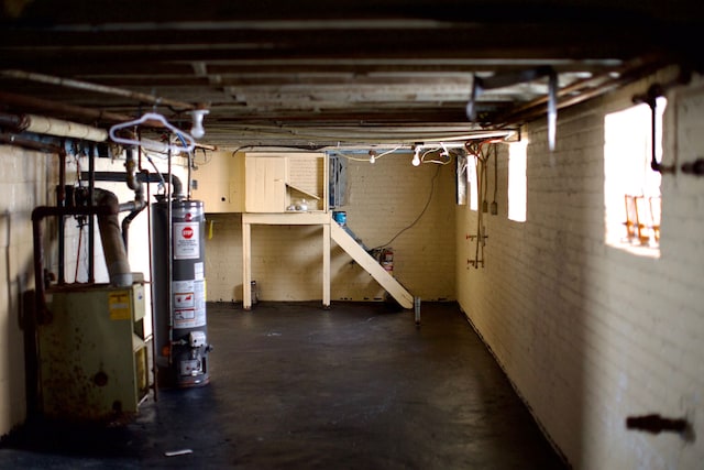 basement featuring brick wall and water heater