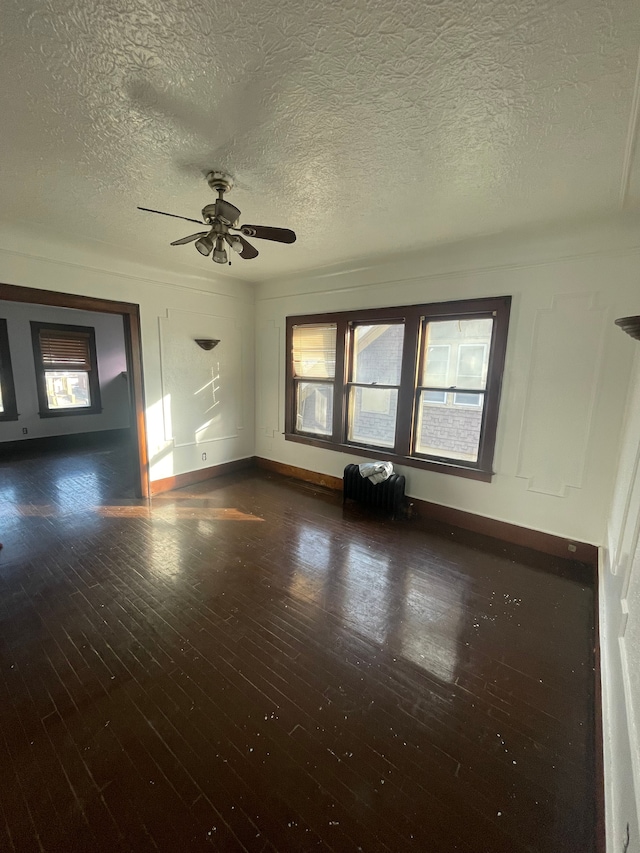 unfurnished room with ceiling fan, dark hardwood / wood-style flooring, and a textured ceiling