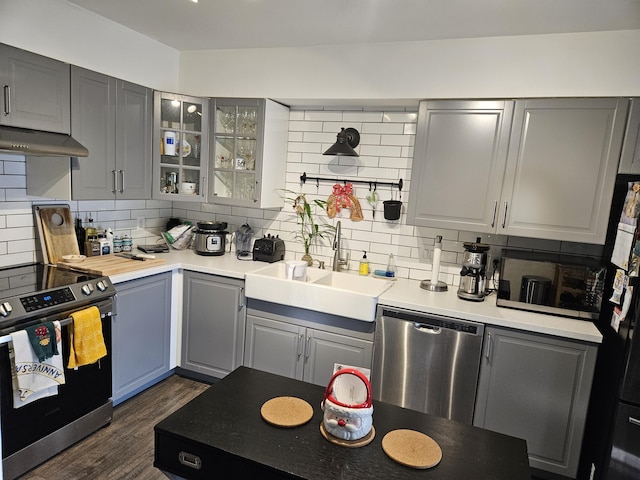 kitchen featuring appliances with stainless steel finishes, backsplash, gray cabinetry, extractor fan, and sink