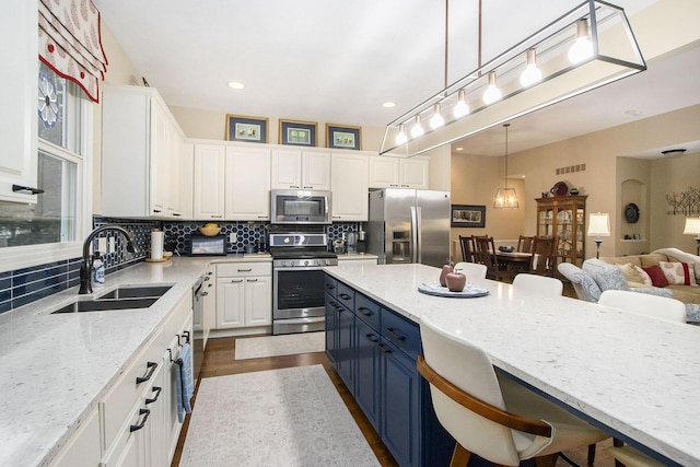 kitchen with a breakfast bar, white cabinets, stainless steel appliances, and blue cabinets