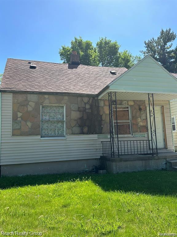 19664 Fleming St, Detroit, MI 48234 - bungalow-style house featuring a front lawn, covered porch, a shingled roof, stone siding, and a chimney