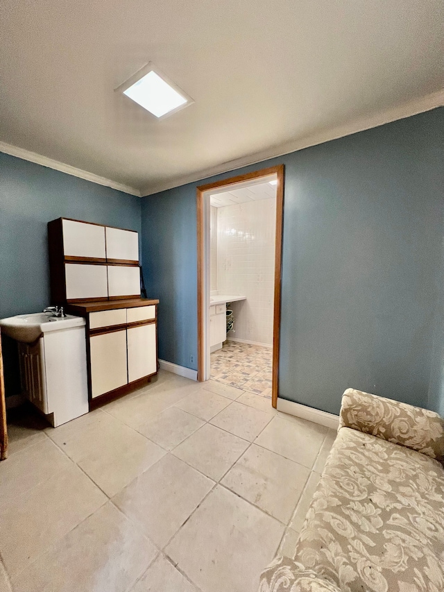 kitchen featuring light tile patterned flooring, ornamental molding, and sink