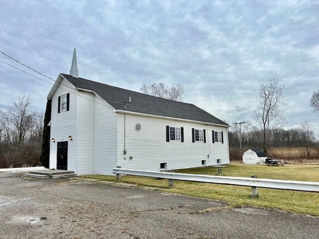 view of side of home featuring a shed and a lawn