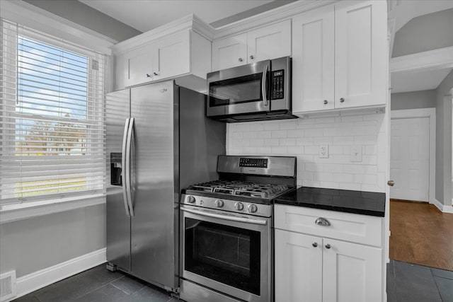 kitchen with white cabinets, appliances with stainless steel finishes, backsplash, and dark tile patterned flooring