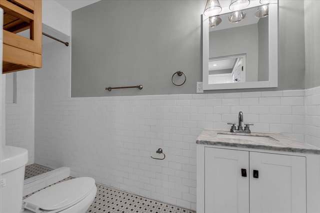 bathroom featuring tile patterned flooring, a shower, toilet, vanity, and tile walls