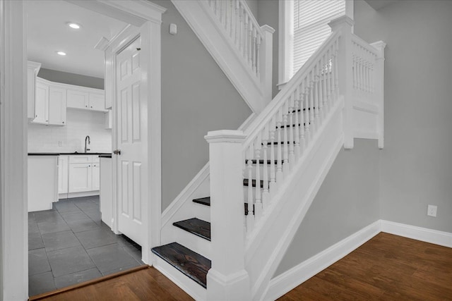 stairs featuring tile patterned flooring and sink