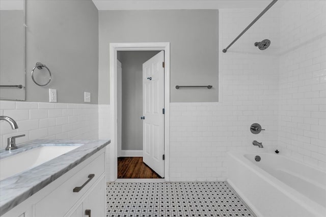 bathroom with shower / washtub combination, vanity, and tile walls