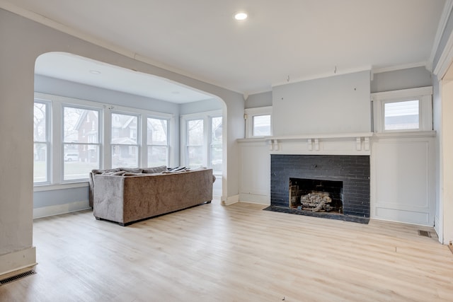 living room featuring ornamental molding, a fireplace, and light hardwood / wood-style flooring