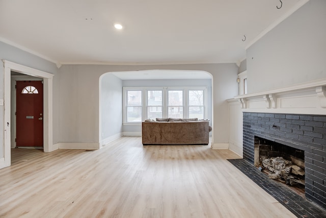 unfurnished living room featuring ornamental molding, a fireplace, and light hardwood / wood-style flooring