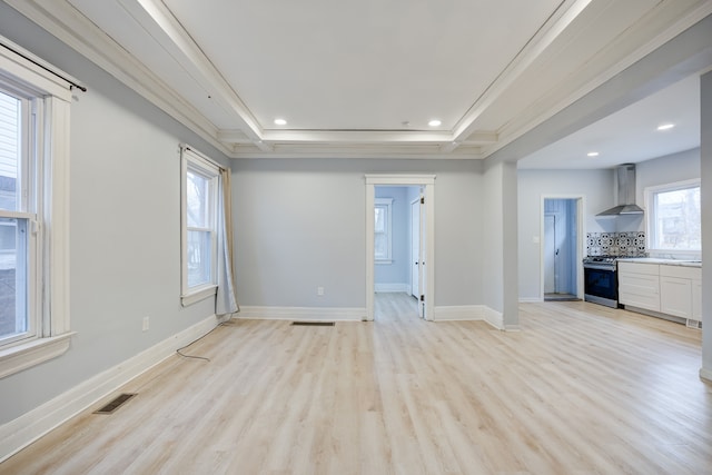 interior space with light wood-type flooring, a raised ceiling, and ornamental molding