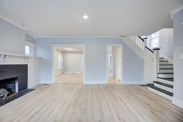 unfurnished living room featuring a fireplace, light hardwood / wood-style floors, and crown molding