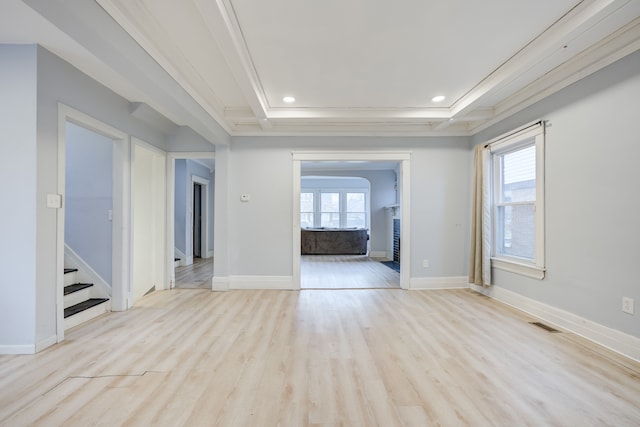 unfurnished living room featuring light hardwood / wood-style floors, a raised ceiling, and ornamental molding