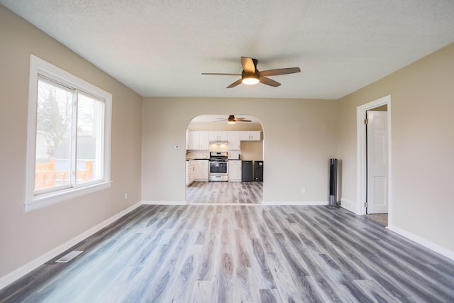 unfurnished living room with ceiling fan, light wood-type flooring, and a textured ceiling