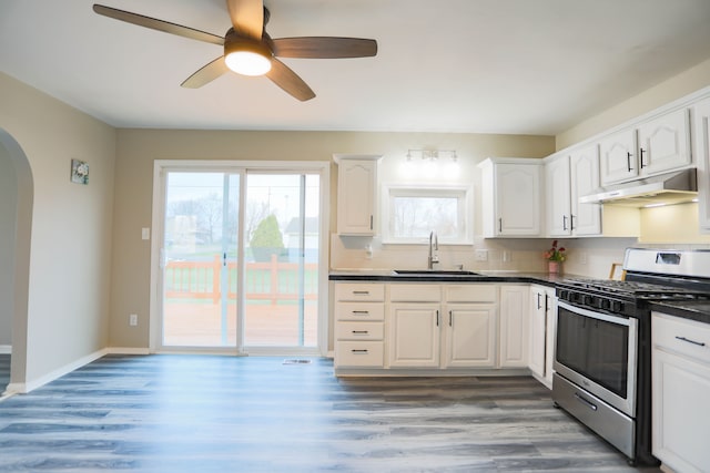 kitchen with sink, stainless steel gas range, hardwood / wood-style flooring, ceiling fan, and white cabinetry