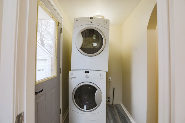 washroom with stacked washer / dryer and dark wood-type flooring