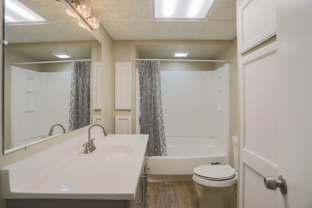 full bathroom featuring a paneled ceiling, vanity, hardwood / wood-style flooring, toilet, and shower / tub combo with curtain