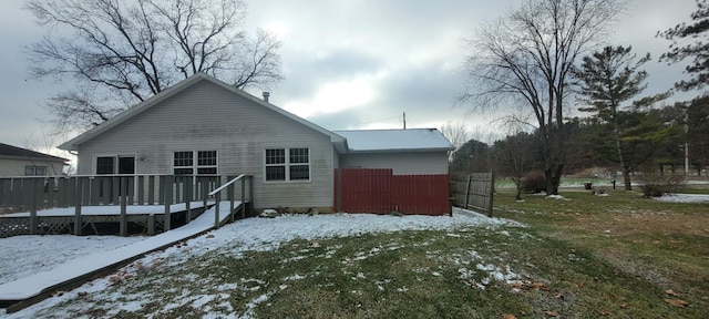 snow covered rear of property featuring a yard and a deck