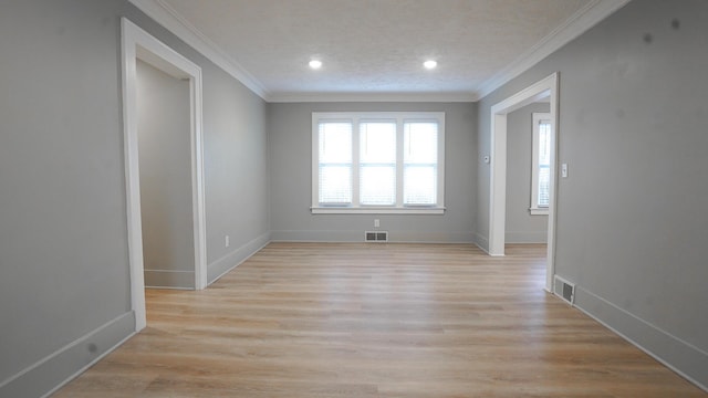 empty room with a textured ceiling, ornamental molding, and light hardwood / wood-style flooring