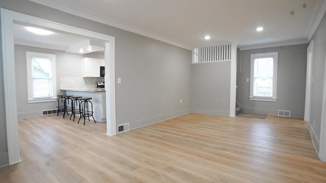 spare room featuring ornamental molding, light hardwood / wood-style floors, and a healthy amount of sunlight