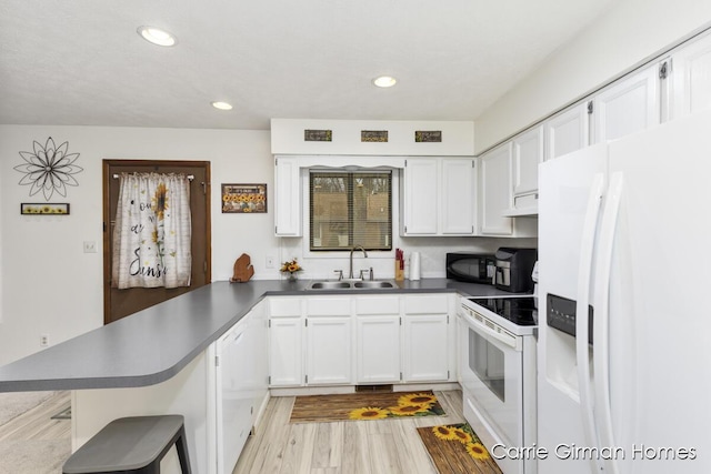 kitchen with white cabinetry, sink, white appliances, and kitchen peninsula