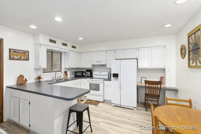 kitchen with white appliances, white cabinets, sink, light hardwood / wood-style flooring, and kitchen peninsula