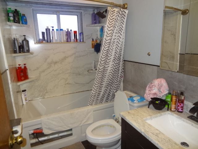 full bathroom featuring shower / bath combo, toilet, backsplash, and vanity