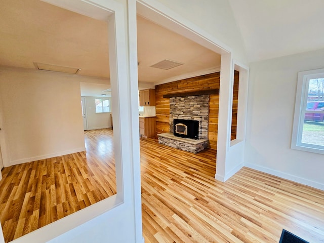 unfurnished living room with a wood stove, wooden walls, and light hardwood / wood-style floors