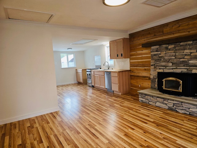 kitchen with a stone fireplace, crown molding, sink, light hardwood / wood-style flooring, and stainless steel appliances