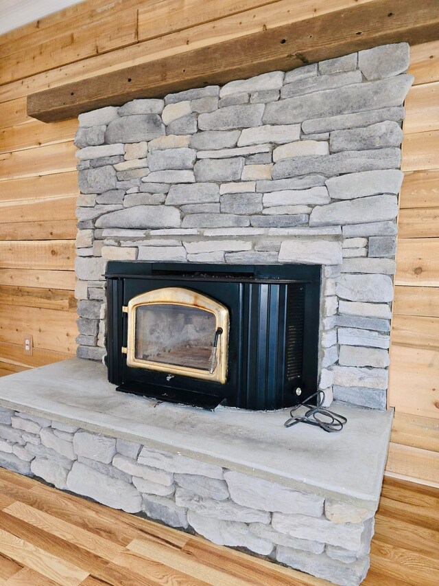 interior details with hardwood / wood-style floors, a wood stove, and wood walls