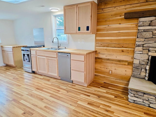 kitchen with light brown cabinetry, sink, stainless steel appliances, and light hardwood / wood-style flooring