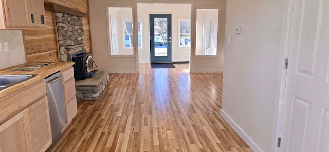 entryway with light hardwood / wood-style floors and a wood stove